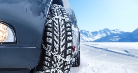 a close-up of a car tire wrapped in a tire chain while on a snowy road