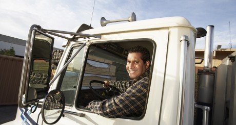 Un camionero sonriendo y mirando por la ventana.