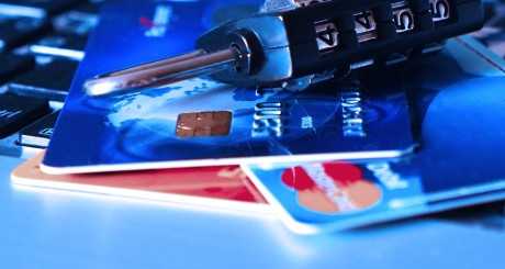 dos tarjetas de crédito y un candado abierto al lado de un teclado de computadora