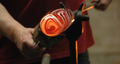 a glassblower working a piece of molten glass