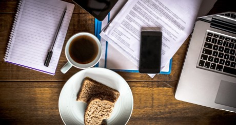 una taza de café, una calculadora y un cuaderno sobre un escritorio