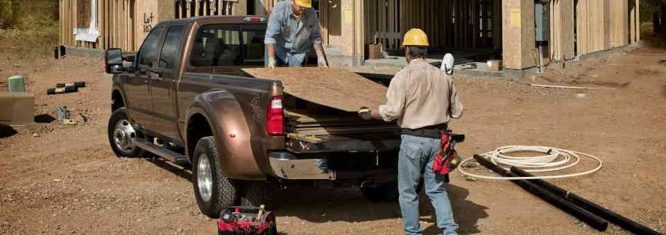 two contractors unloading materials from their pickup truck at a residential construction site